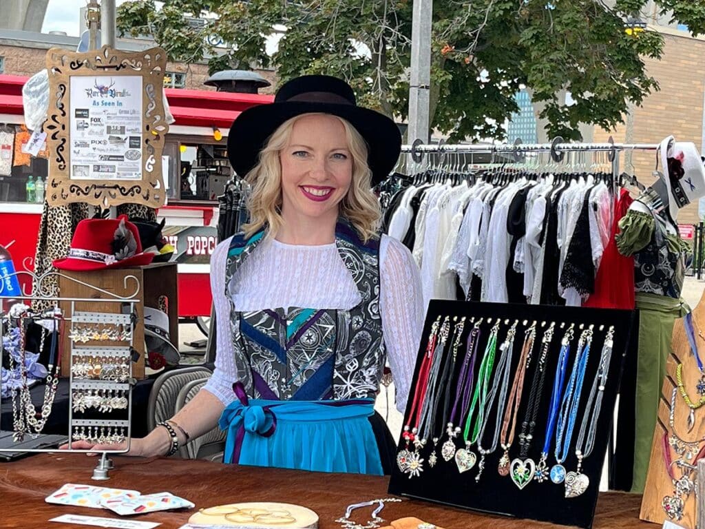 Designer of Rare Dirndl smiling at a booth selling high fashion Dirndls worn for special occasions, traditions and celebration